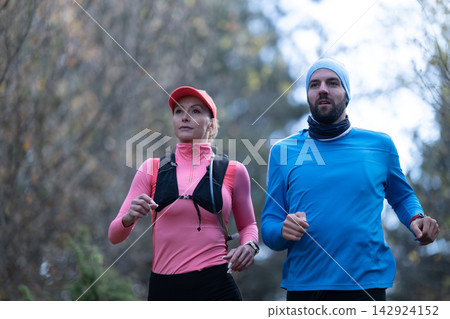 Couple Running on Trail Together Outdoor Fitness Training in Cold Weather Active Lifestyle Couple Running on Trail Together Outdoor Fitness Training in Cold Weather Active Lifestyle 142924152