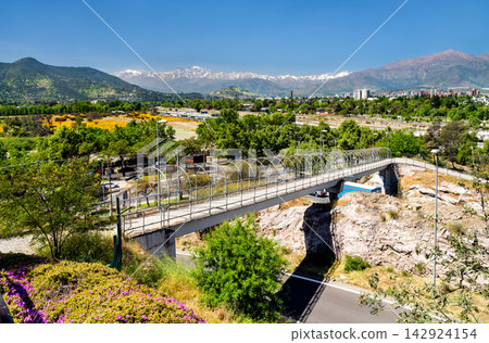 A pedestrian bridge at Santiago Metropolitan Park with the snow capped Andes mountains in the background under a clear blue sky in Santiago, Chile. A pedestrian bridge at Santiago Metropolitan Park with the snow capped Andes mountains in the background under a clear blue sky in Santiago, Chile. 142924154
