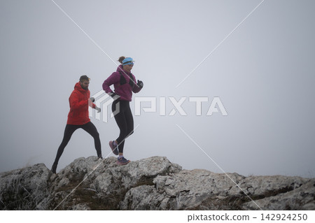 Trail Running Couple on Foggy Mountain Ridge With Headlamps for Winter Fitness Training 142924250