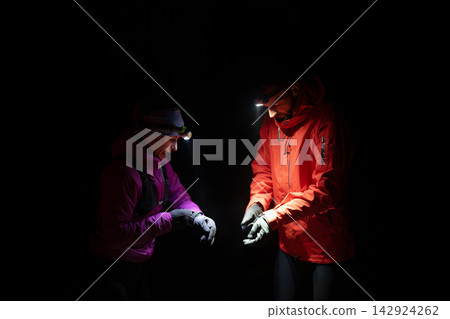 Night Hikers With Headlamps Checking Gear During Cold Weather Adventure In Dark Outdoors Night Hikers With Headlamps Checking Gear During Cold Weather Adventure In Dark Outdoors 142924262