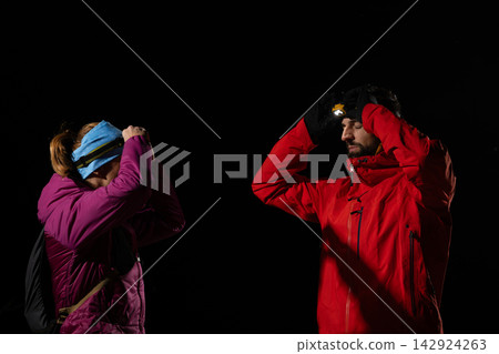 Night Hikers Wearing Headlamps Adjusting Gear During Cold Winter Outdoor Trek Night Hikers Wearing Headlamps Adjusting Gear During Cold Winter Outdoor Trek 142924263