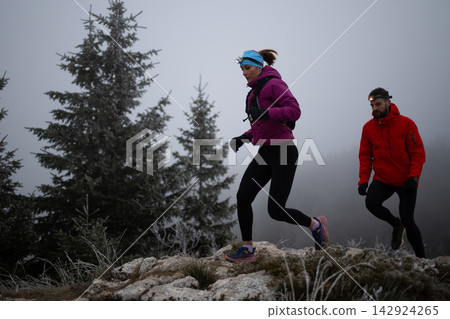 Trail Running Couple With Headlamps On Frosty Mountain Ridge In Foggy Winter Morning Trail Running Couple With Headlamps On Frosty Mountain Ridge In Foggy Winter Morning 142924265