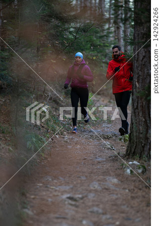 Trail Running Couple Jogging Through Forest Path During Cold Weather Training Session Trail Running Couple Jogging Through Forest Path During Cold Weather Training Session 142924266
