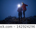 Night Trail Running Couple With Headlamps On Foggy Mountain Path Showing Teamwork And Adventure 142924296