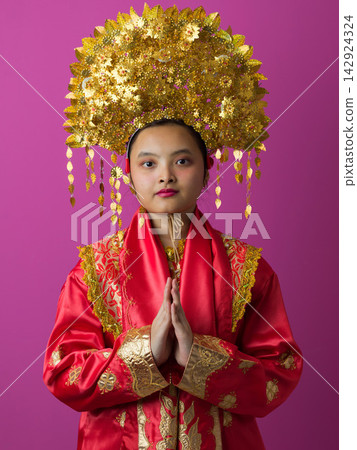 Young Indonesian Asian Girl Wearing Ornate Gold Headdress and Traditional Red Chinese Costume Portrait Young Indonesian Asian Girl Wearing Ornate Gold Headdress and Traditional Red Chinese Costume Portrait 142924324