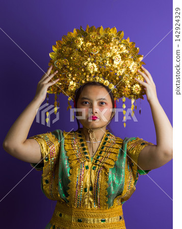 Portrait Of Woman Wearing Traditional Southeast Asian Gold Headdress And Ornate Festival Costume Portrait Of Woman Wearing Traditional Southeast Asian Gold Headdress And Ornate Festival Costume 142924329