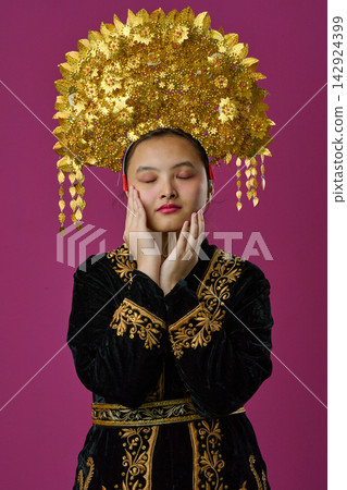 Portrait Of Young Indonesian Asian Woman Wearing Ornate Gold Traditional Headdress And Embroidered Black Costume Portrait Of Young Indonesian Asian Woman Wearing Ornate Gold Traditional Headdress And Embroidered Black Costume 142924399