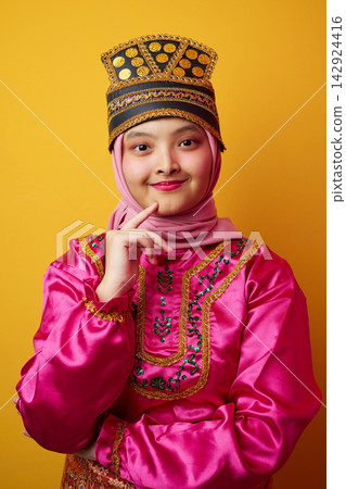 Smiling Young Indonesian Asian Girl in Pink Hijab and Traditional Festive Costume With Embroidered Hat Portrait Smiling Young Indonesian Asian Girl in Pink Hijab and Traditional Festive Costume With Embroidered Hat Portrait 142924416