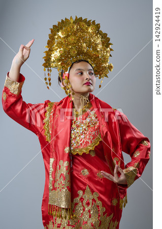 Young Woman in Red and Gold Traditional Southeast Asian Costume With Ornate Golden Headdress Young Woman in Red and Gold Traditional Southeast Asian Costume With Ornate Golden Headdress 142924419