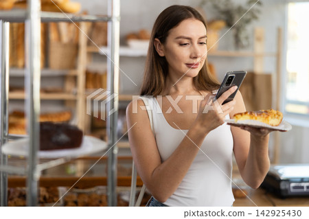 Young girl scanning pastry on paper plate in bakery Young girl scanning pastry on paper plate in bakery 142925430