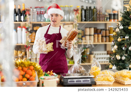 European guy seller stands in trading hall grocery, offer to buy sweets at New Year Eve European guy seller stands in trading hall grocery, offer to buy sweets at New Year Eve 142925433