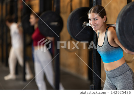 Woman doing strength training with a barbell Woman doing strength training with a barbell 142925486