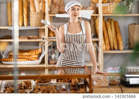 Young woman seller at counter in bakery Young woman seller at counter in bakery 142925666