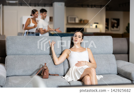Young woman choosing convenient sofa in furniture shop Young woman choosing convenient sofa in furniture shop 142925682