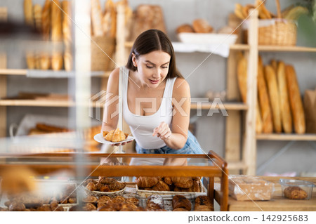 Young female buyer choosing croissants in bakery Young female buyer choosing croissants in bakery 142925683