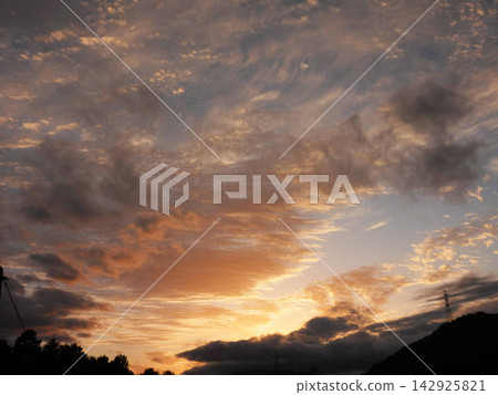 傍晚的天空被染成了金色,雲朵呈現出一幅動感而美麗的景象。 傍晚的天空被染成了金色,雲朵呈現出一幅動感而美麗的景象。 142925821