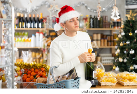 Young guy choosing wine in grocery store Young guy choosing wine in grocery store 142925842