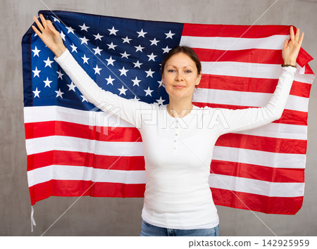 Cheerful woman posing with flag of United States in studio 142925959