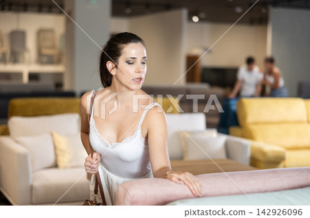 Portrait of woman consumer choosing sofa in furniture shop Portrait of woman consumer choosing sofa in furniture shop 142926096