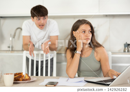 Young guy quarrels with young woman working at laptop Young guy quarrels with young woman working at laptop 142926282
