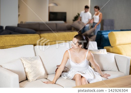 Young woman choosing convenient sofa in furniture shop Young woman choosing convenient sofa in furniture shop 142926304