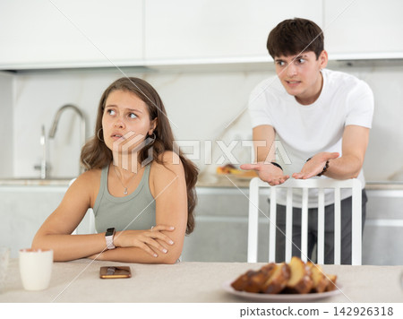 Young guy quarrels with young woman in kitchen Young guy quarrels with young woman in kitchen 142926318