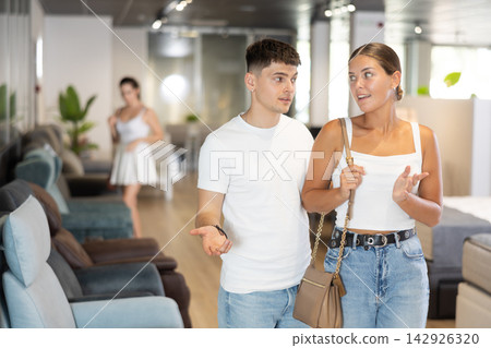 Young couple watching large stock of goods in furniture shop Young couple watching large stock of goods in furniture shop 142926320