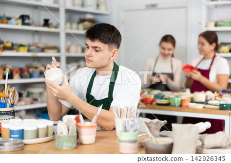 Concentrated young man engraving on clay cup Concentrated young man engraving on clay cup 142926345
