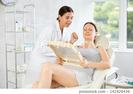 Young woman cosmetologists examines face of female patient Young woman cosmetologists examines face of female patient 142926436