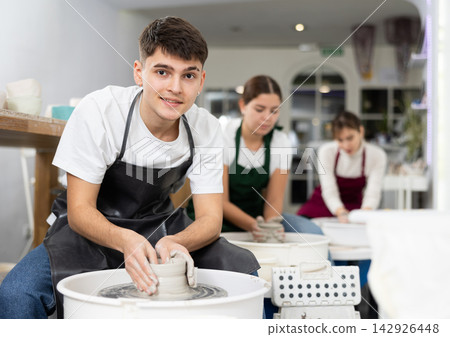 Young man working with pottery wheel Young man working with pottery wheel 142926448