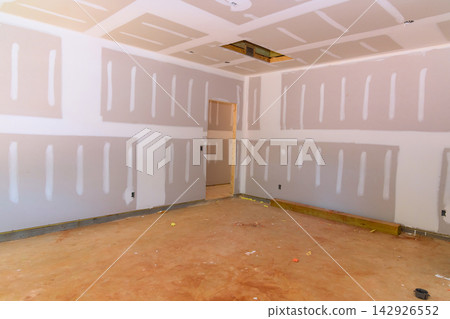 Construction site of an interior room with drywall installed unfinished floor Construction site of an interior room with drywall installed unfinished floor 142926552