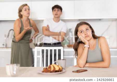 Mother-in-law and son scold young daughter-in-law in home kitchen Mother-in-law and son scold young daughter-in-law in home kitchen 142926661