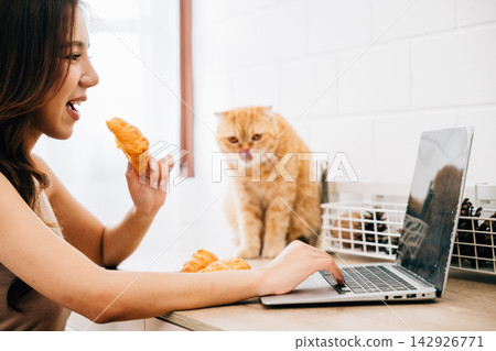 In this heartwarming portrait, a woman at her desk strikes the perfect balance between work and pet cuddles with her Scottish Fold cat, emphasizing the bond of togetherness. In this heartwarming portrait, a woman at her desk strikes the perfect balance between work and pet cuddles with her Scottish Fold cat, emphasizing the bond of togetherness. 142926771