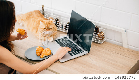 Heartwarming home office portrait, woman exemplifies joy of togetherness with her Scottish Fold cat while focusing on work at her desk, creating harmonious blend of productivity and pet companionship. Heartwarming home office portrait, woman exemplifies joy of togetherness with her Scottish Fold cat while focusing on work at her desk, creating harmonious blend of productivity and pet companionship. 142926773