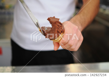 Serving chocolate ice cream in a cone at an outdoor booth Serving chocolate ice cream in a cone at an outdoor booth 142927234