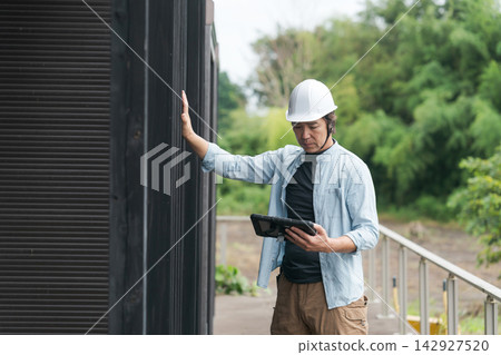 Site supervisor inspecting the exterior walls Site supervisor inspecting the exterior walls 142927520