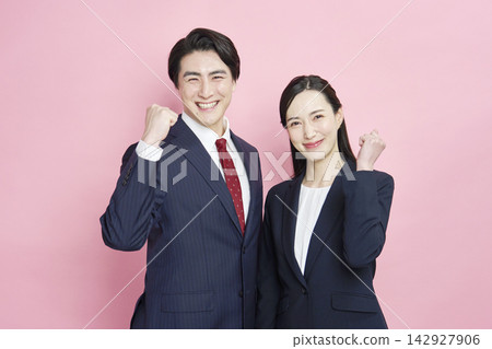 一位商人和一位女商人以粉紅色背景擺出勝利姿勢。 142927906