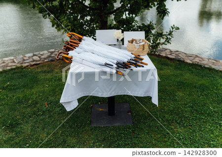 Wedding table with white umbrellas for guests outdoors. Wedding table with white umbrellas for guests outdoors. 142928300