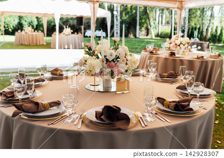 Elegant wedding table setting with floral centerpiece and candles under a marquee tent. Elegant wedding table setting with floral centerpiece and candles under a marquee tent. 142928307