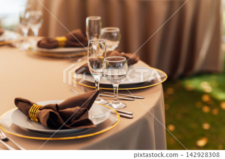 Elegant wedding table setting detail with plates, napkins and golden rings. Elegant wedding table setting detail with plates, napkins and golden rings. 142928308