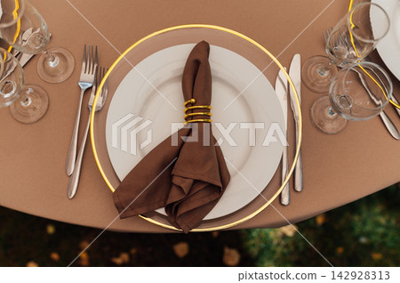 Elegant wedding table setting detail with plates, napkins and golden rings. Elegant wedding table setting detail with plates, napkins and golden rings. 142928313
