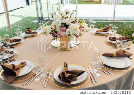 Elegant wedding table setting with floral centerpiece and candles under a marquee tent. Elegant wedding table setting with floral centerpiece and candles under a marquee tent. 142928318