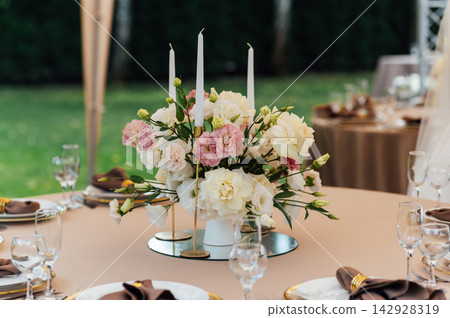 Elegant wedding table setting with floral centerpiece and candles under a marquee tent. Elegant wedding table setting with floral centerpiece and candles under a marquee tent. 142928319