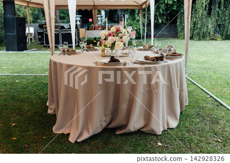 Elegant wedding table setting with floral centerpiece and candles under a marquee tent. Elegant wedding table setting with floral centerpiece and candles under a marquee tent. 142928326