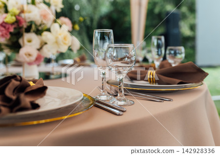 Elegant wedding table setting detail with plates, napkins and golden rings. Elegant wedding table setting detail with plates, napkins and golden rings. 142928336