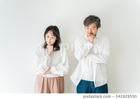 A couple in their 40s, thinking and worrying about their future. Middle-aged people grappling with issues of life and money. A couple in their 40s, thinking and worrying about their future. Middle-aged people grappling with issues of life and money. 142929550