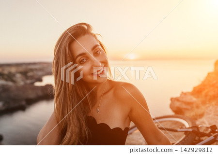 Woman sunset vacation young smiling woman poses on a rocky cliff overlooking the ocean during golden hour at sunset Woman sunset vacation young smiling woman poses on a rocky cliff overlooking the ocean during golden hour at sunset 142929812