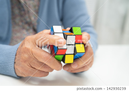 Bangkok, Thailand, December 30, 2025 Asian elderly woman playing Rubik cube game. Bangkok, Thailand, December 30, 2025 Asian elderly woman playing Rubik cube game. 142930239