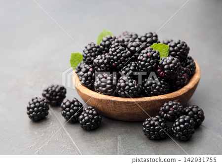 Blackberry in wooden plate on concrete backgrounds Blackberry in wooden plate on concrete backgrounds 142931755