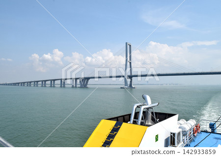 View of a bridge stretching across the sea, connecting two islands against a backdrop of beautiful blue sky and water View of a bridge stretching across the sea, connecting two islands against a backdrop of beautiful blue sky and water 142933859